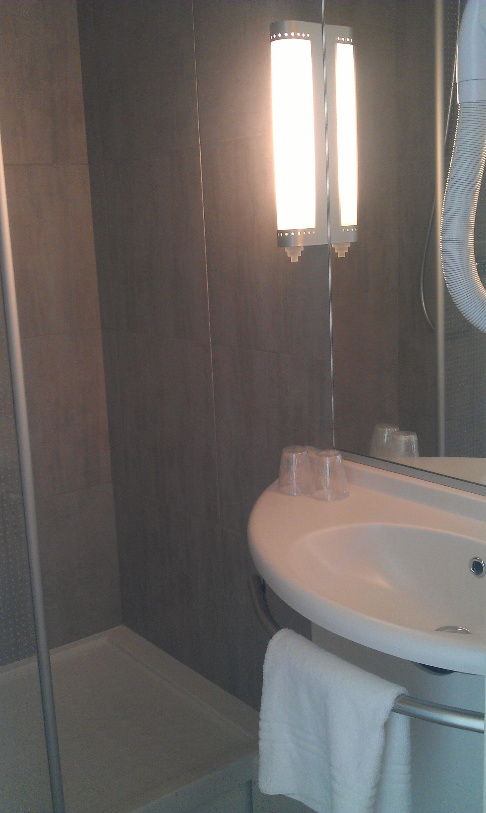 Une salle de bain avec un lavabo blanc, un miroir et une serviette suspendue à un porte-serviettes.