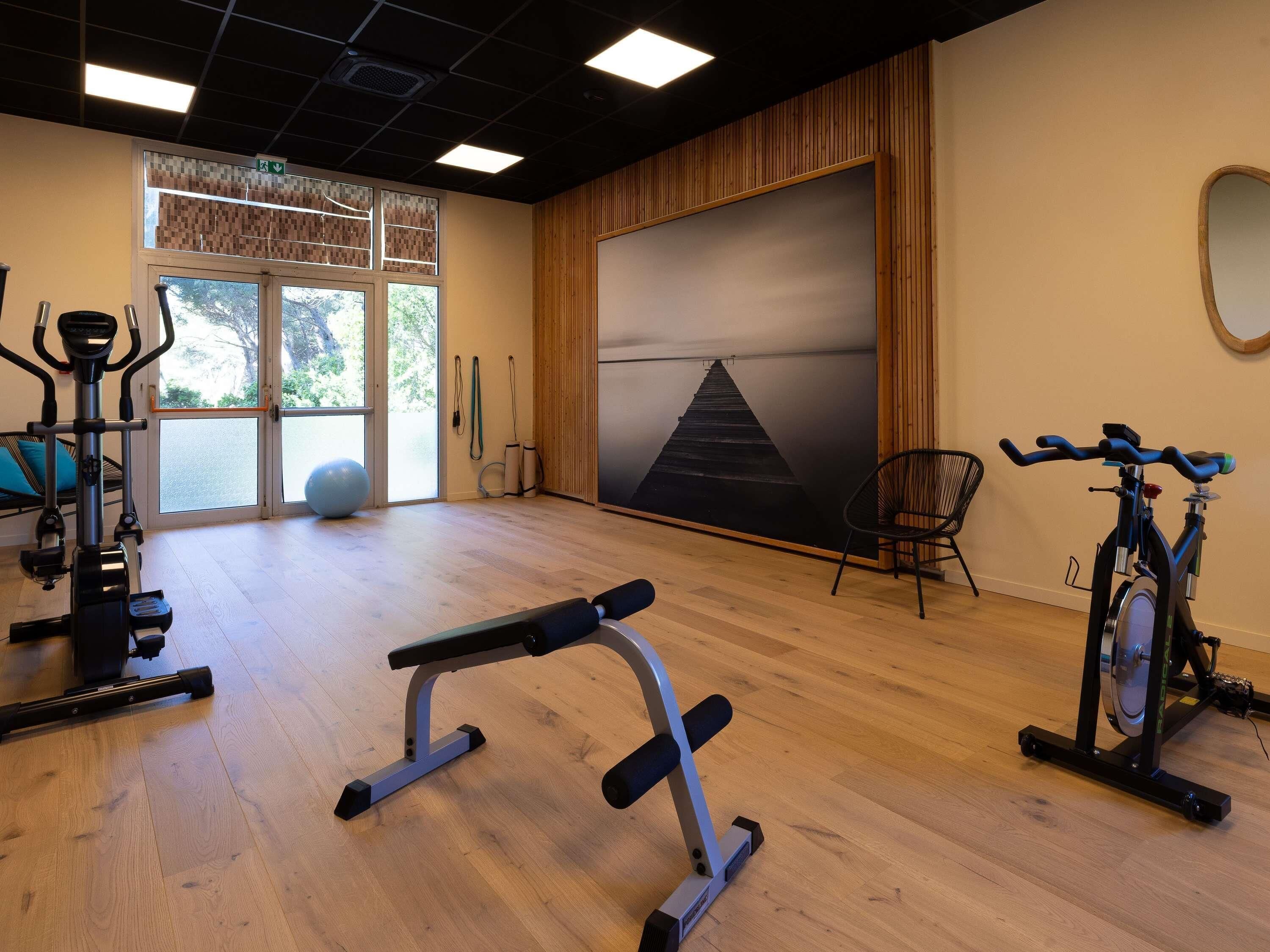 A gym with exercise equipment, a large window, and a view of trees.