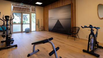 A gym with exercise equipment, a large window, and a view of trees.