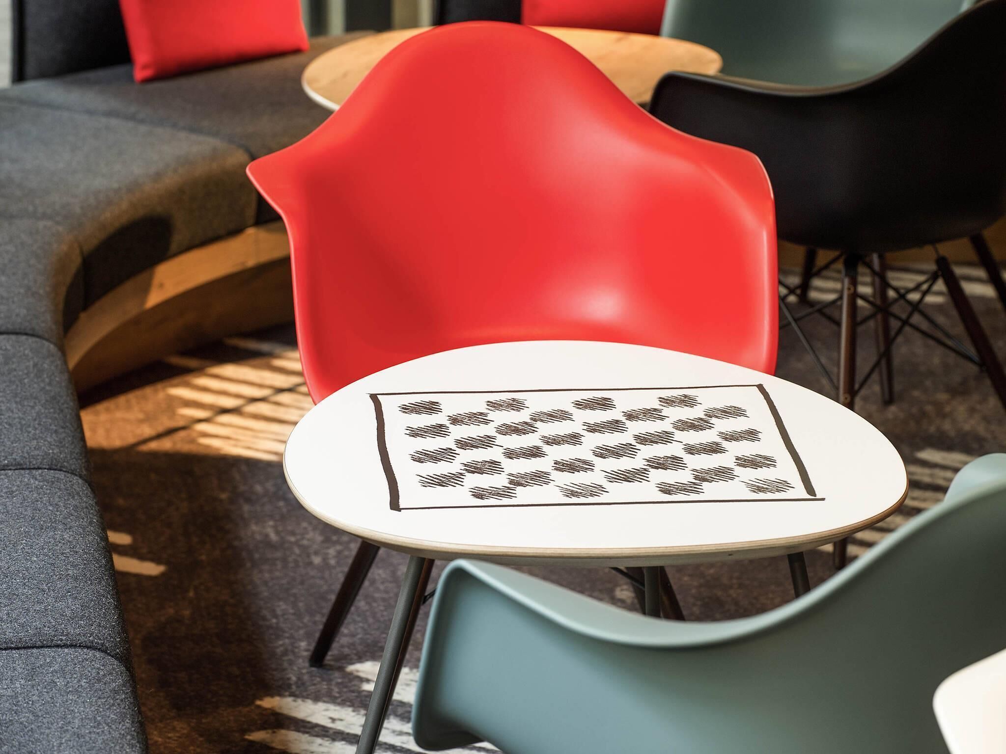 A modern interior with a red chair, a round table with a patterned tabletop, and a grey sofa.