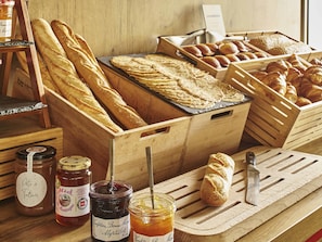 Un comptoir en bois où sont exposés divers produits de boulangerie, des pots de confitures et un couteau à pain.