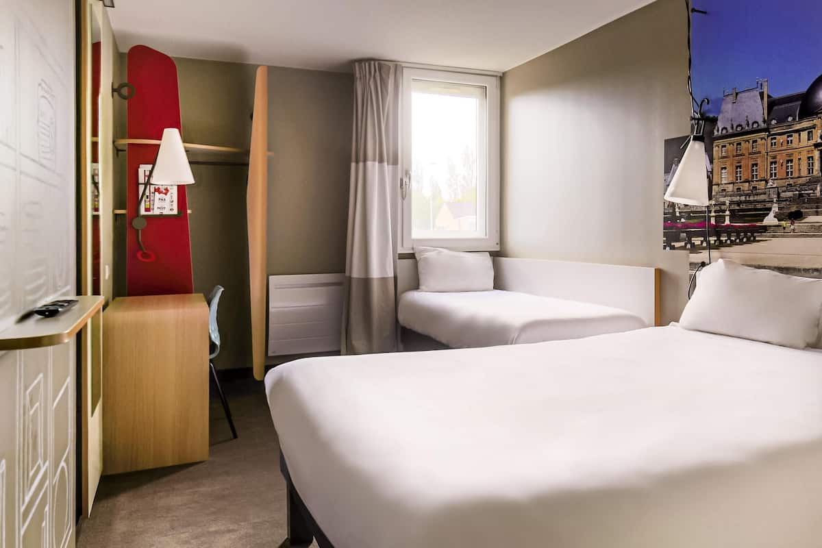 Une chambre d’hôtel avec un grand lit, un bureau, une chaise et une fenêtre avec des rideaux.