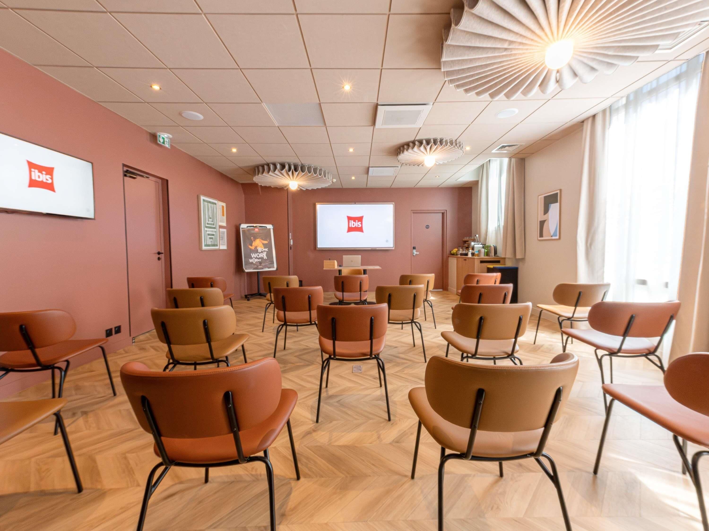 A conference room with a whiteboard, a projector screen displaying 'ibis,' and a presentation on the wall.