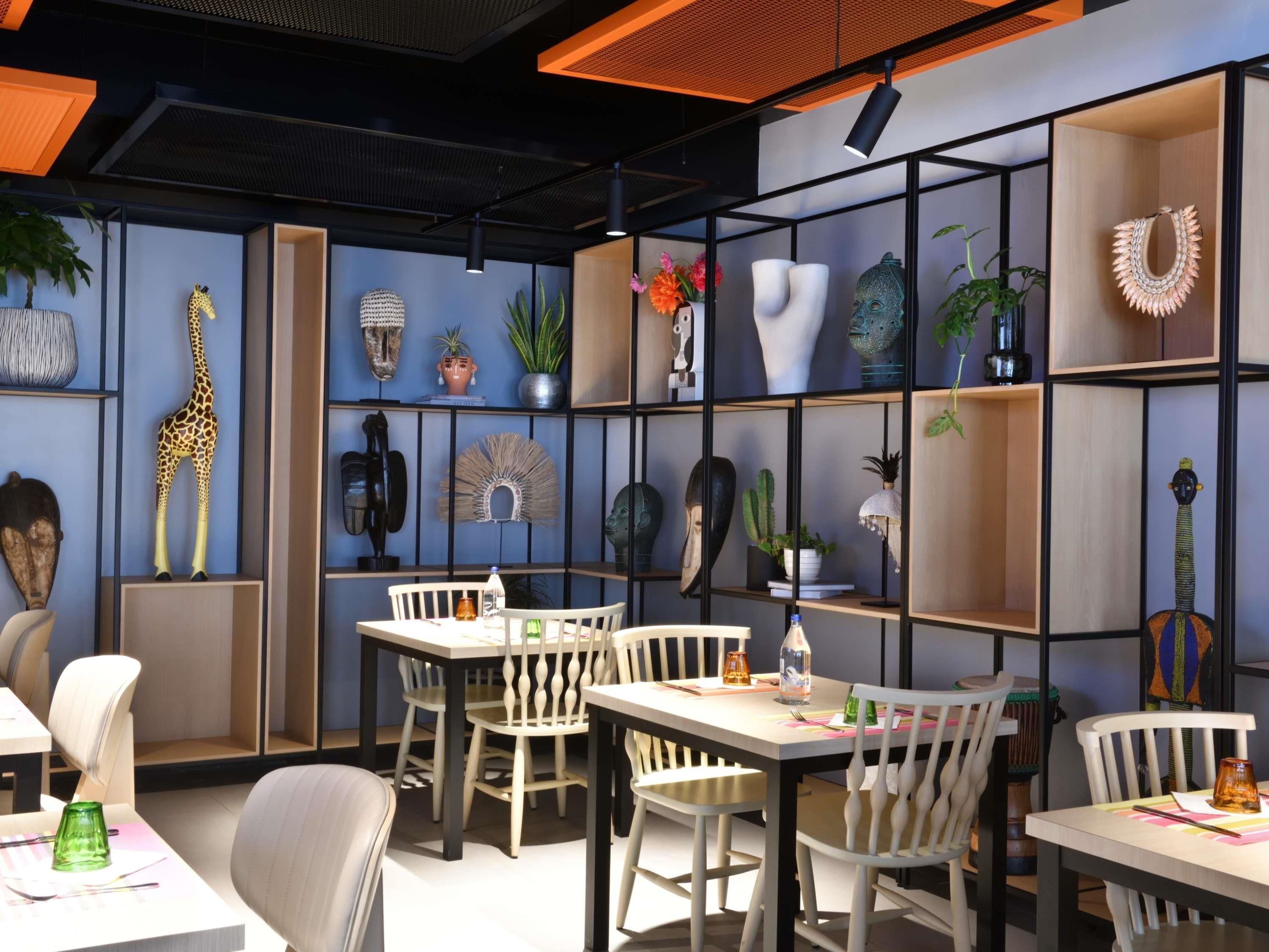 A modern interior with a dining area, shelves with decorative items, and a giraffe sculpture.