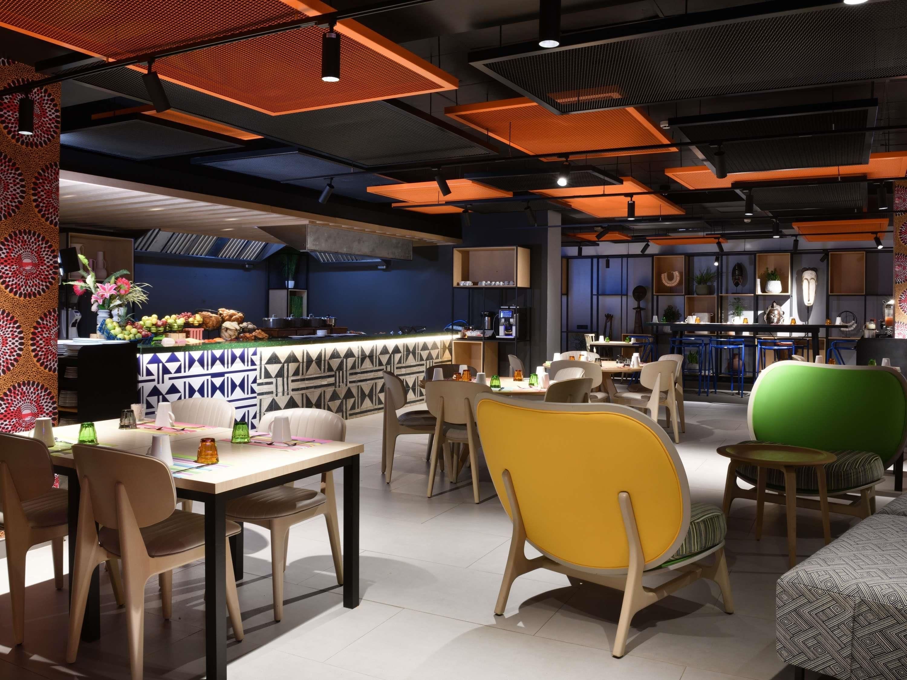 A modern restaurant interior with a bar area, dining tables, and chairs.