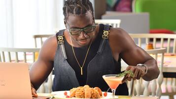 A person seated at a table with a laptop, a plate of food, and a drink.