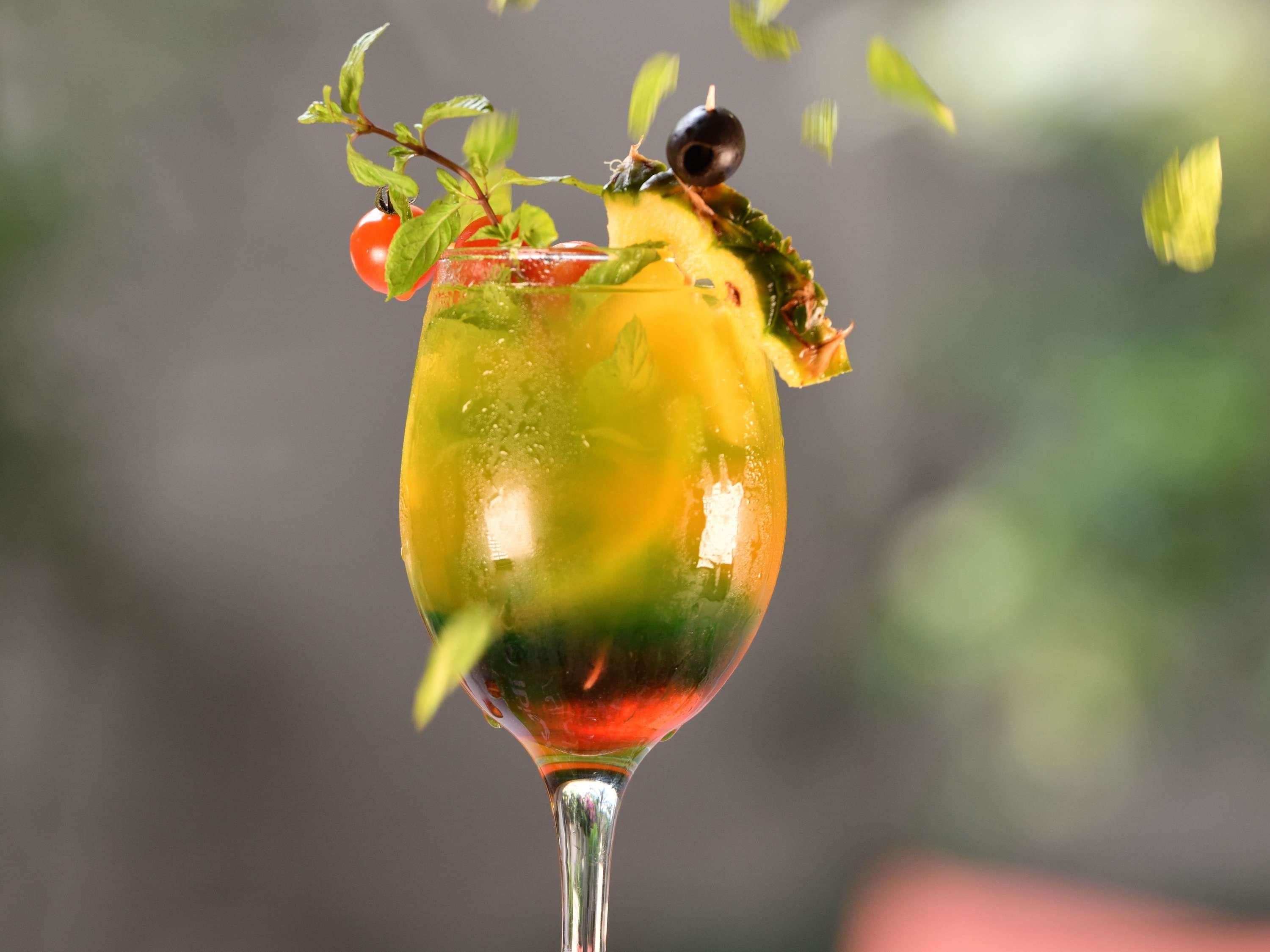 A cocktail glass with a garnish, clear liquid, and a blurred background.