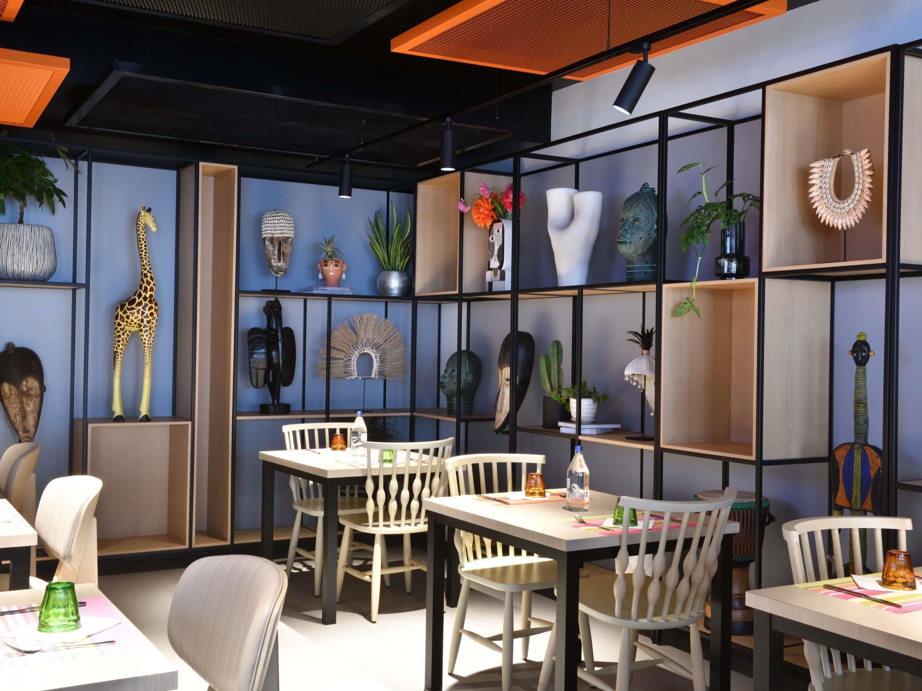 A modern interior with a dining area, shelves with various decorative items, and a giraffe sculpture.