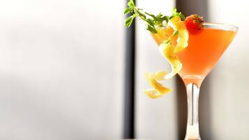 Un cóctel en una copa de martini con una guarnición, sobre un fondo desenfocado.