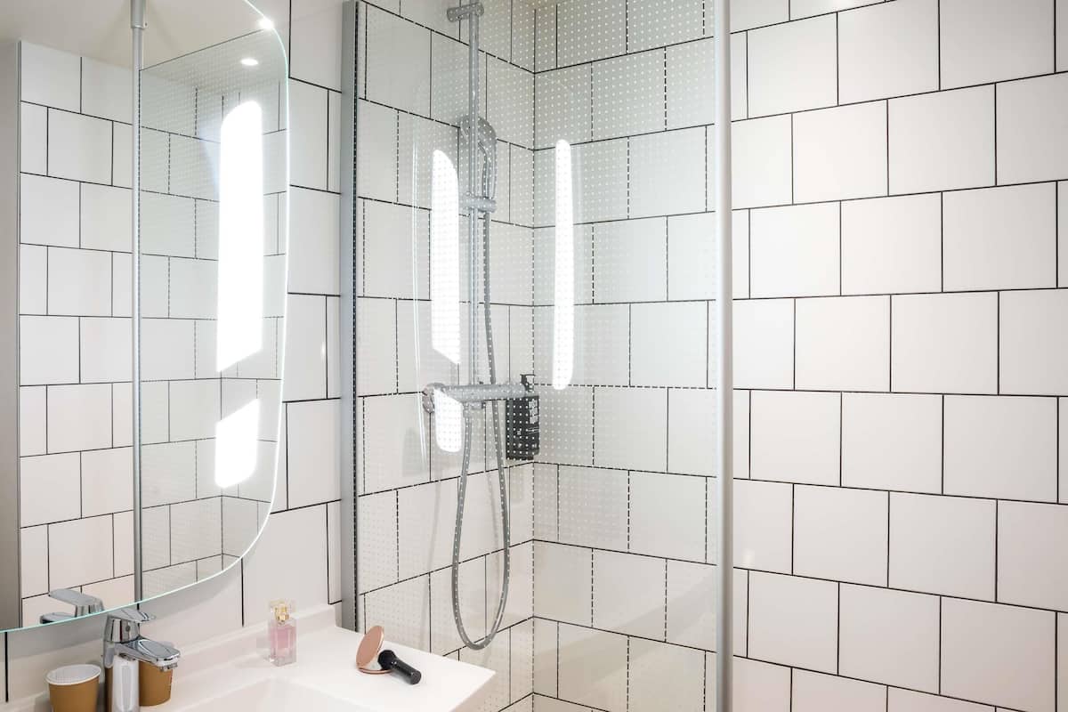A modern bathroom with a glass-enclosed shower, a white sink with a mirror, and a toilet.