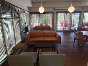 En modern inredning med en soffa, stolar, ett bord och stora fönster med persienner.