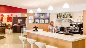 A bar area with a counter, stools, a coffee machine, and a menu board. - ibis Setubal (Setubal)