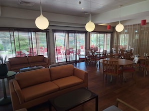 A modern interior with a sofa, dining tables, and hanging pendant lights. - ibis Setubal (Setubal)