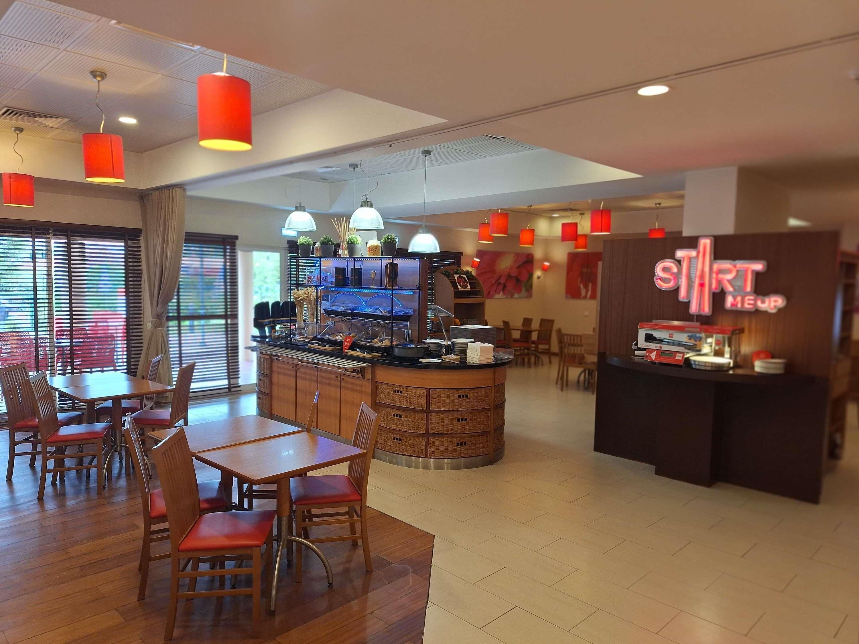 Un restaurante con barra central, zona de comedor con mesas y sillas, y un letrero de neón.