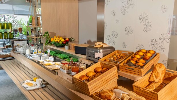 Un bufé con diversas opciones de comida, incluyendo frutas, pasteles y pan.