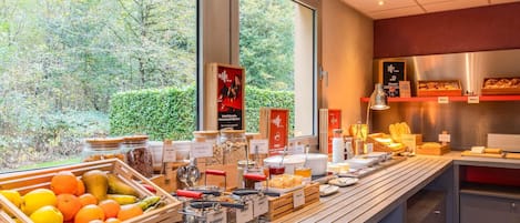 A breakfast buffet with various food items and a view of trees outside.