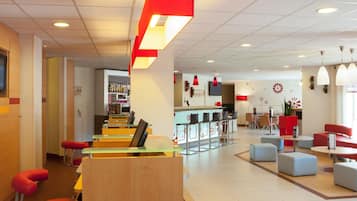 Un moderno vestíbulo de hotel con zona de bar, asientos y un mostrador de recepción.
