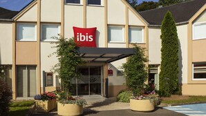 Un hotel con un llamativo letrero rojo de 'ibis', diseño arquitectónico moderno y jardines bien cuidados.