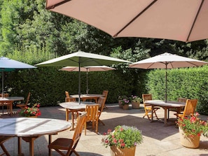 An outdoor patio area with round tables and chairs, surrounded by large umbrellas providing shade. - Ibis Jouy en Josas Velizy (Jouy-en-Josas)
