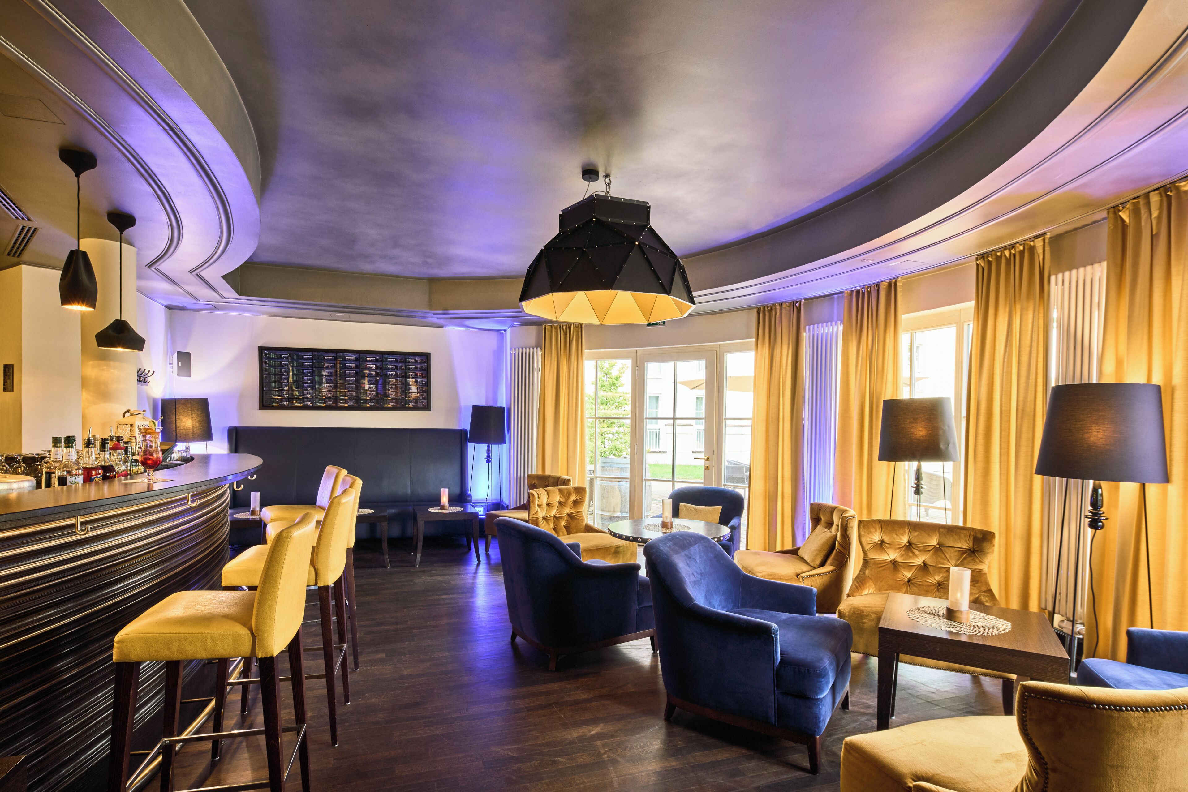 Zona de bar con taburetes, techo alto con diseño original y área de estar con sillas y una mesa.