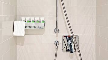 A shower with a handheld showerhead, a wall-mounted faucet, and a soap dispenser.