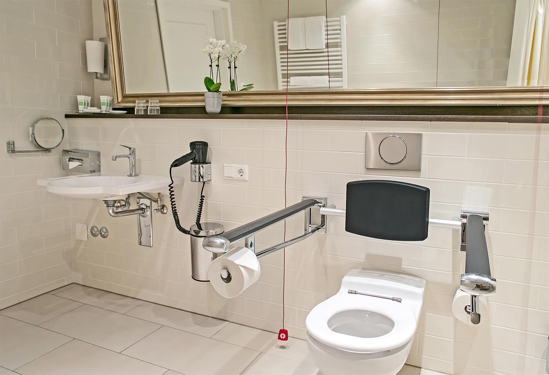 A modern bathroom with a toilet, bidet, sink, and a towel rack, and a mirror.