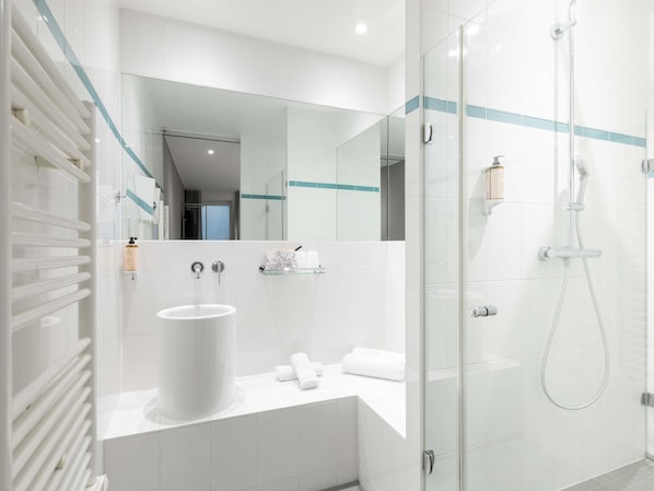 Une salle de bain moderne avec une douche à parois de verre, un lavabo blanc et un miroir.