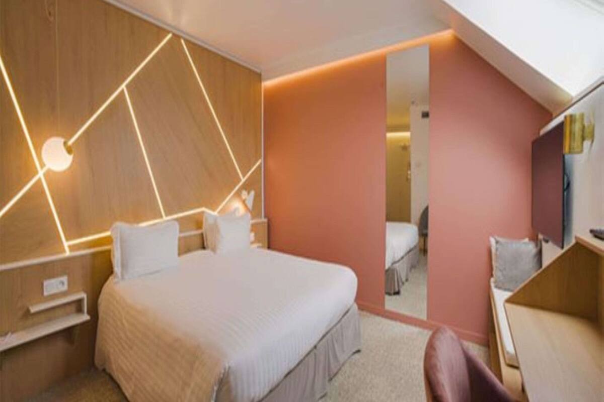 A modern bedroom with a large bed, a desk, and a mirror.