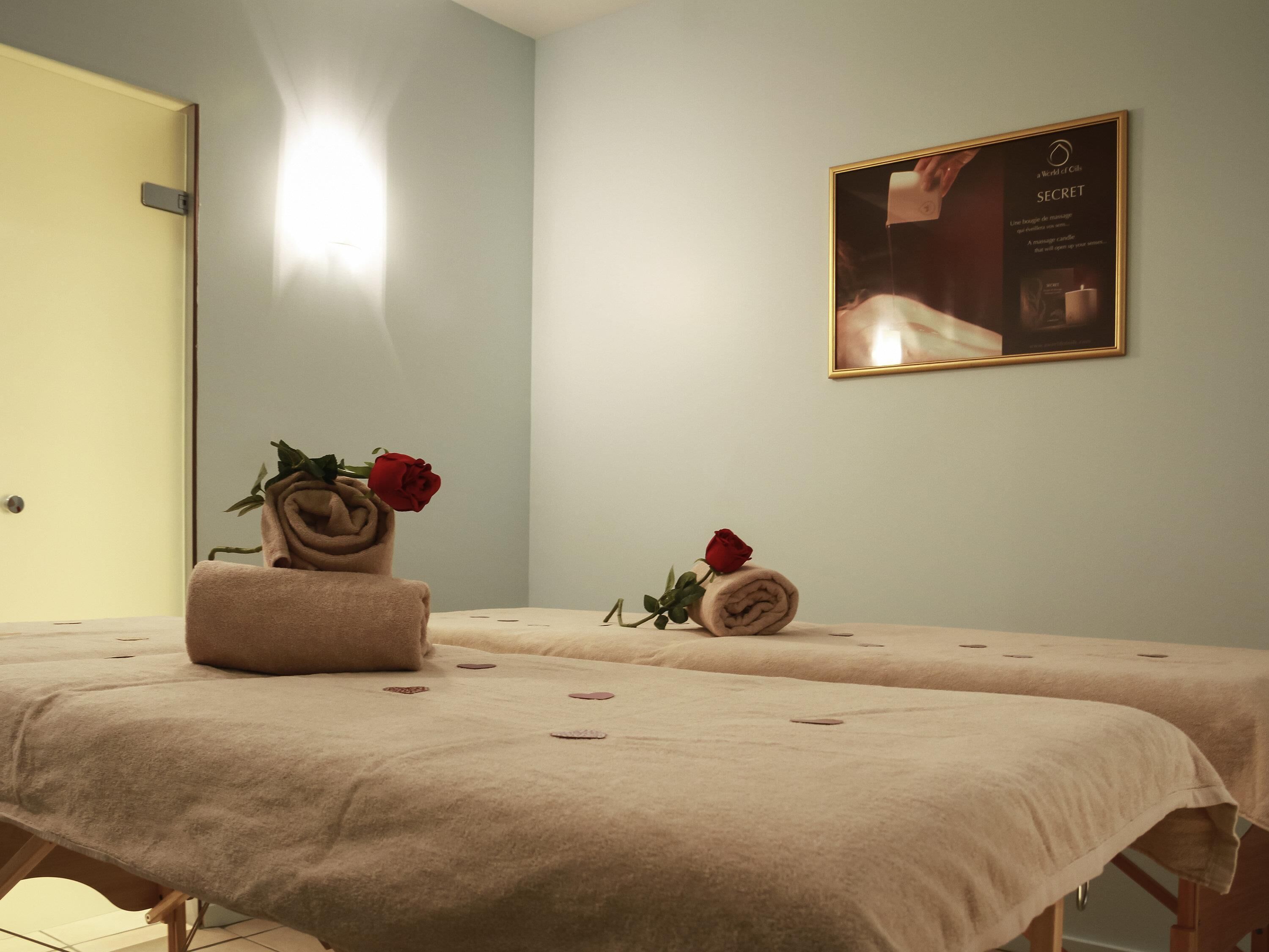 A spa room with two beds, a framed advertisement on the wall, and a door.