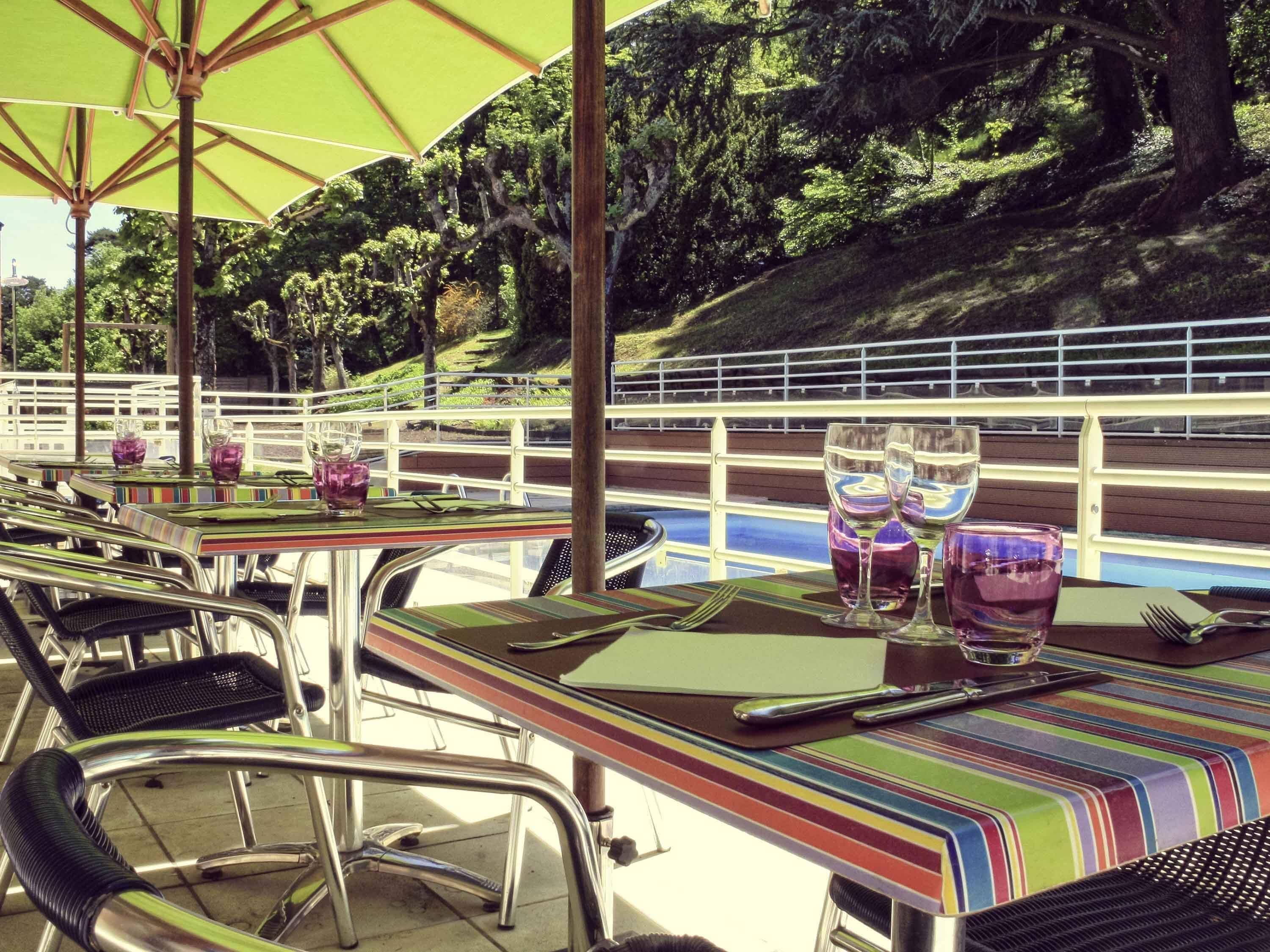 An outdoor dining area with tables, chairs, and a pool view.