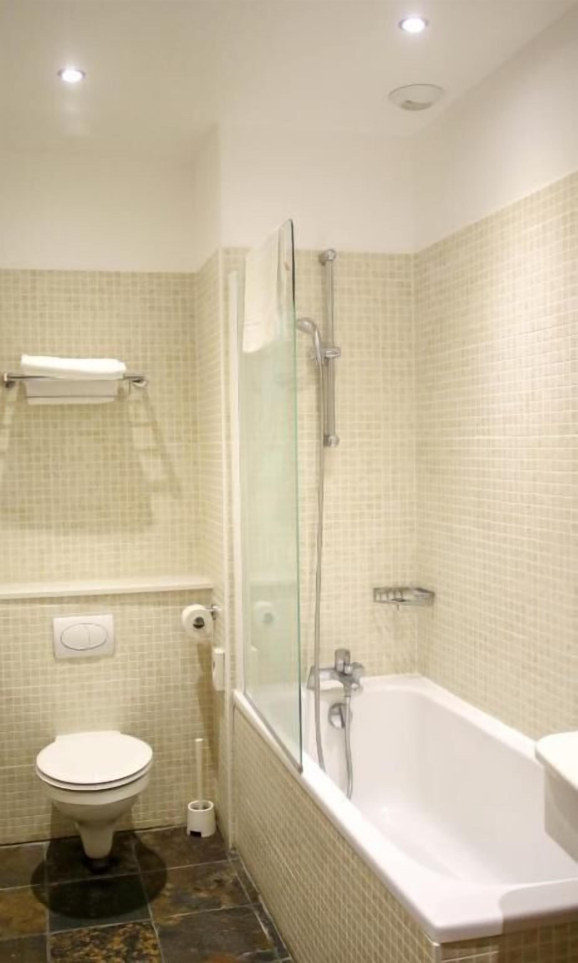 A bathroom with a toilet, a glass-enclosed shower, and a bathtub.
