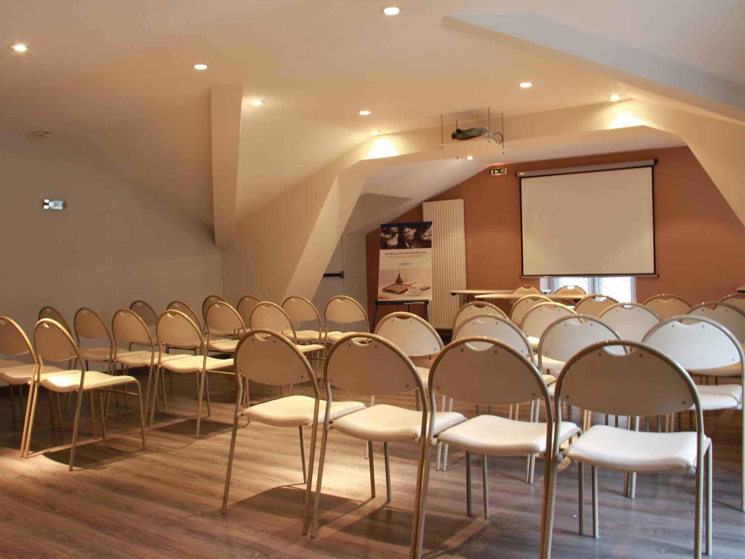 A conference room with rows of chairs, a projector screen, and a podium.