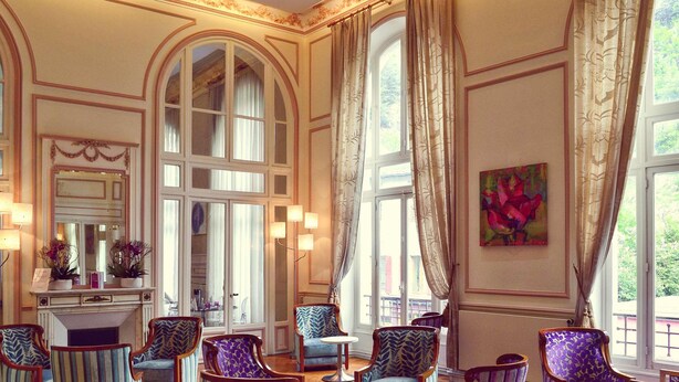 A spacious room with multiple seating areas, large windows, and a fireplace.