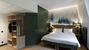 A bedroom with a bed, a wardrobe, and a wall-mounted headboard.