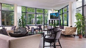 A spacious indoor area with large windows, comfortable seating, and a flat-screen TV.