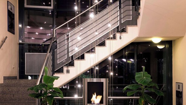 A modern interior with a staircase, a fireplace, and two potted plants.