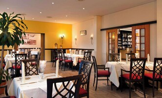 Un restaurante con mesas dispuestas para comer, sillas y una zona de bar.