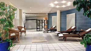A modern indoor relaxation area with wicker chairs, lounge chairs, and potted plants.