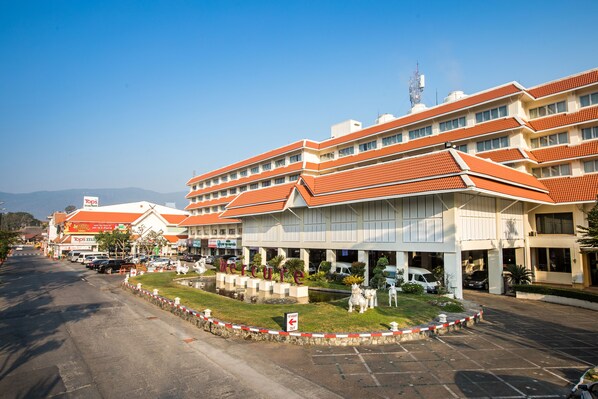 A hotel with multiple floors, a central courtyard, and a parking area.