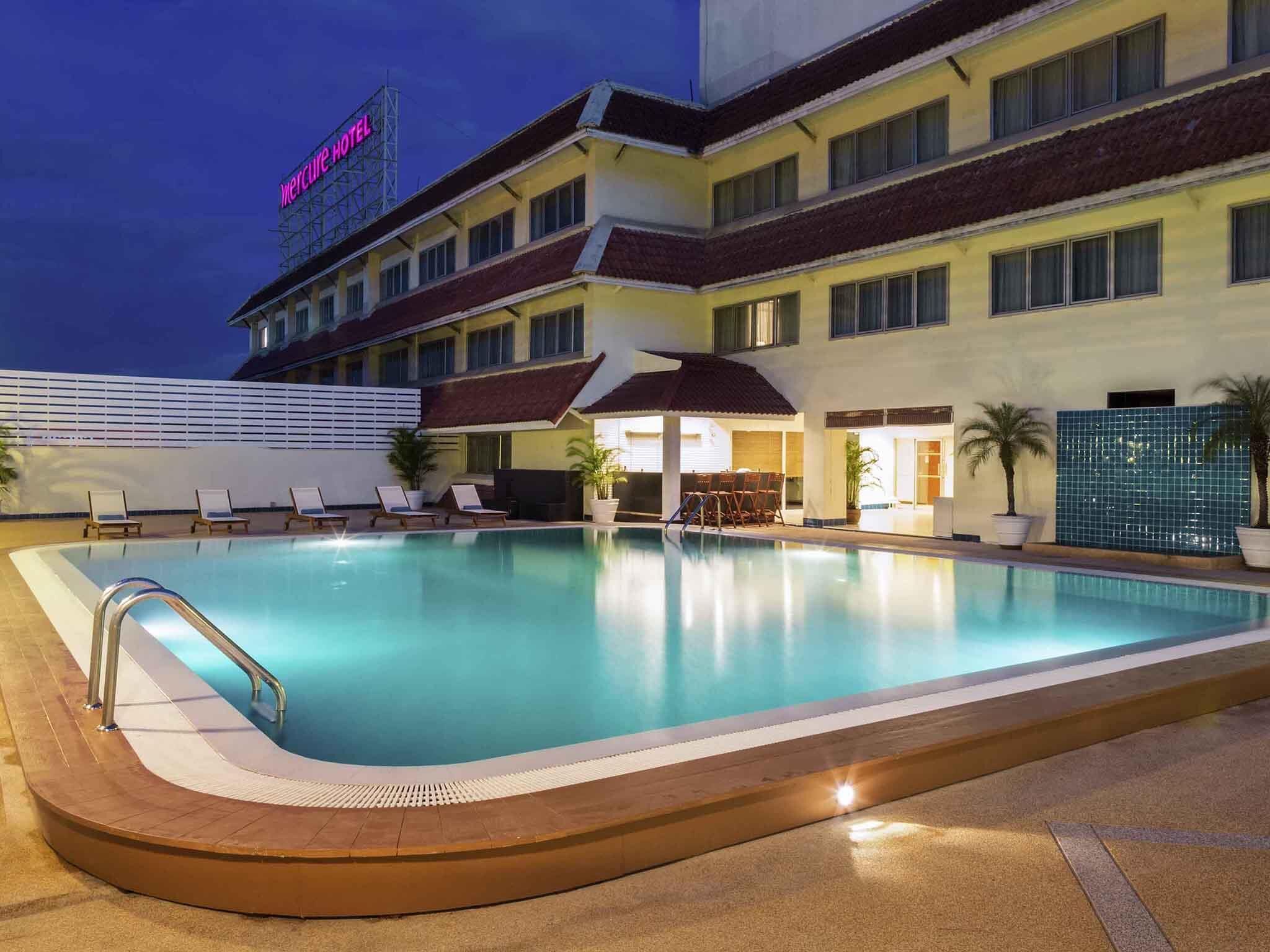 A hotel with a swimming pool, lounge chairs, and a sign indicating the hotel name.