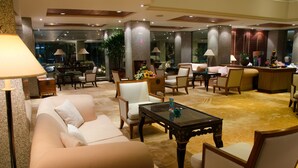 A spacious lobby with a sofa, chairs, a coffee table, and a reception desk. - Mercure Chiang Mai (Chiang Mai)