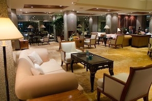 A spacious lobby with a sofa, chairs, a coffee table, and a reception desk.