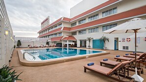 A swimming pool area with lounge chairs and a poolside table. - Mercure Chiang Mai (Chiang Mai)