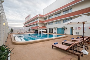 A swimming pool area with lounge chairs and a poolside table.