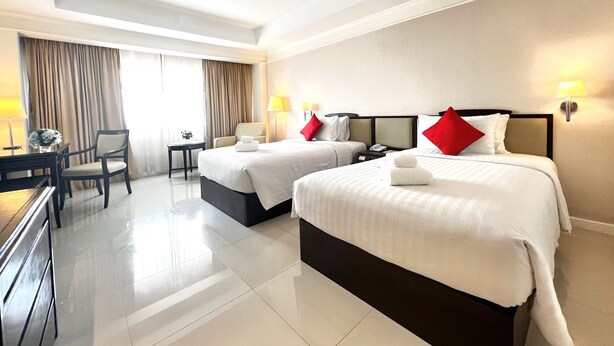 A hotel room with two beds, a desk, chairs, and a lamp. - Mercure Chiang Mai (Chiang Mai)