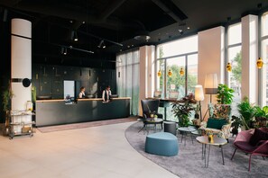 A modern reception area with a reception desk, seating, and large windows. - Sunday Hotel Leipzig (Leipzig)