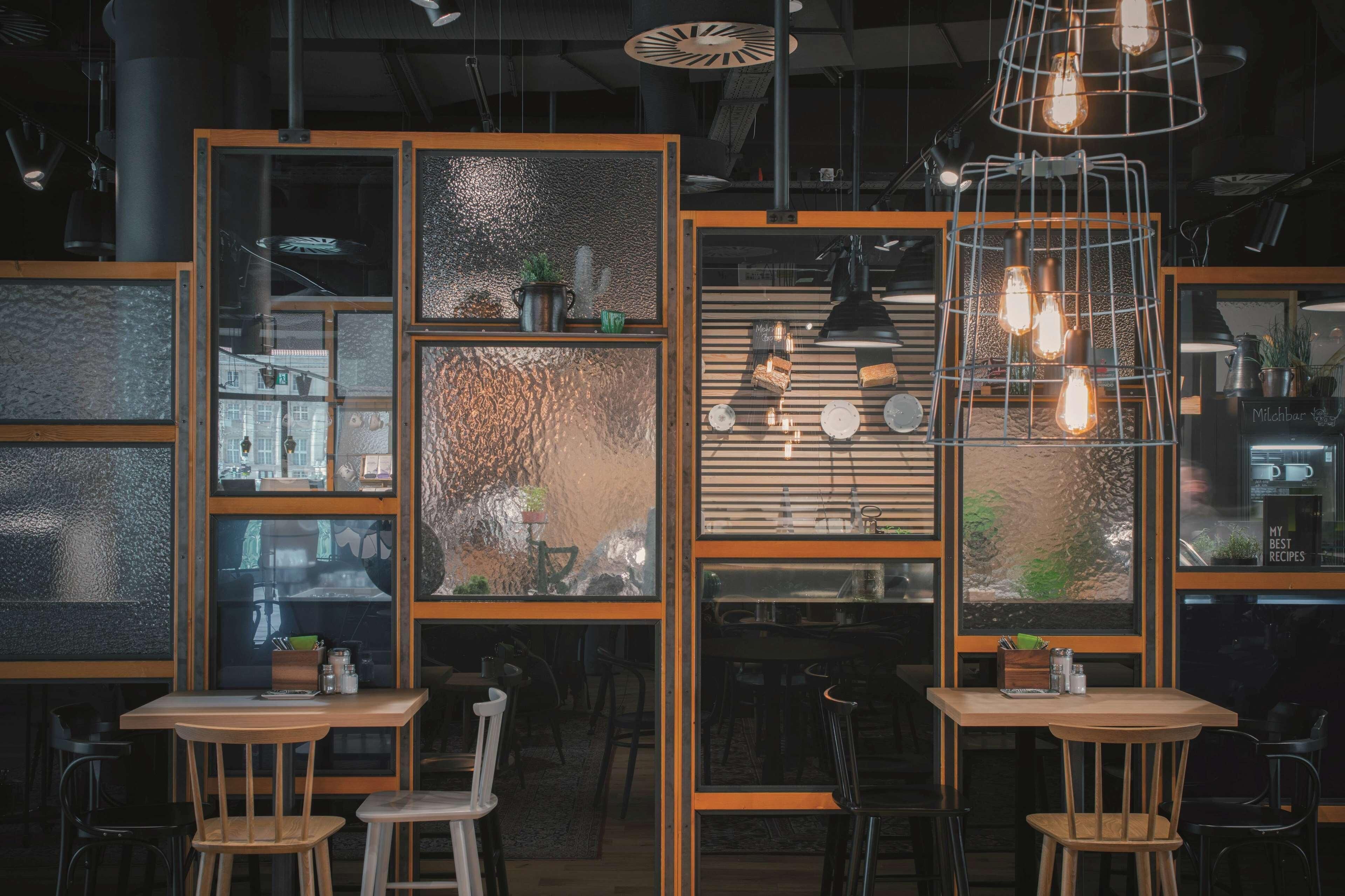 Un interior moderno con mesas y sillas de madera, y un elemento decorativo de iluminación.