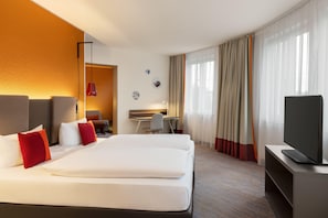 A hotel room with a large bed, a desk, a chair, and a television. - Vienna House Easy by Wyndham Leipzig (Leipzig)