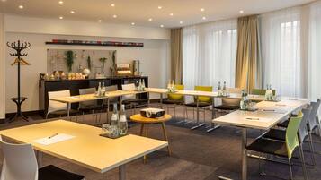 A modern conference room with multiple tables and chairs, equipped with water bottles and a projector.