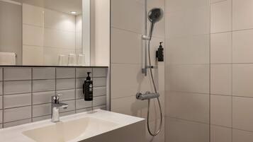 A modern bathroom with a white sink, a handheld showerhead, and a wall-mounted mirror.